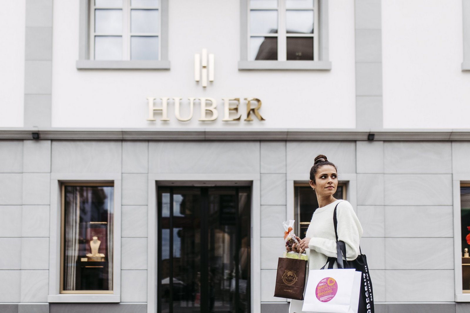 Frau mit einer Shoppingtasche vor dem Geschäft Huber