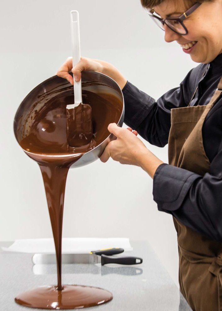 Eine junge Frau gießt flüssige Schokolade auf ihren Arbeitstisch