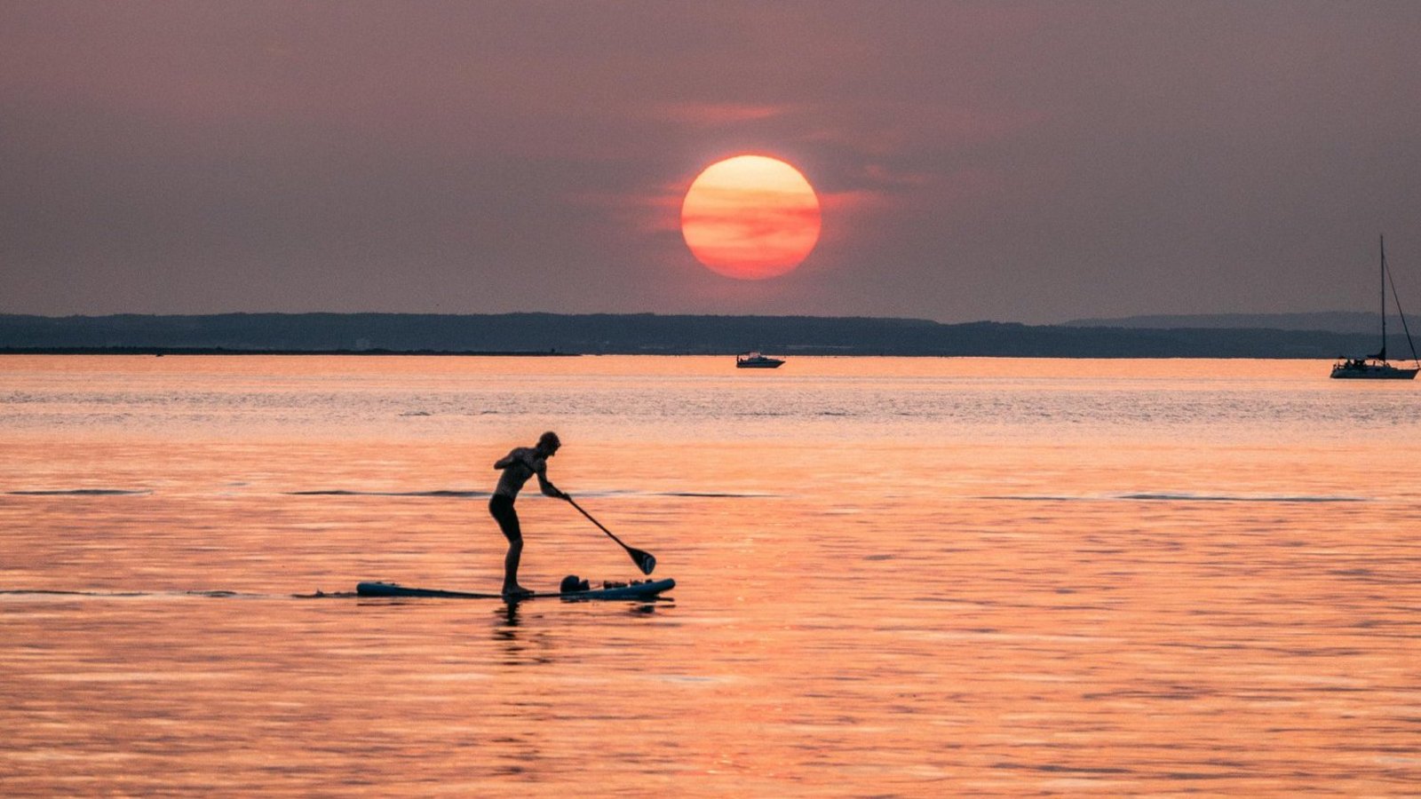 Standuppaddler auf dem Wasser bei Sonnenuntergang