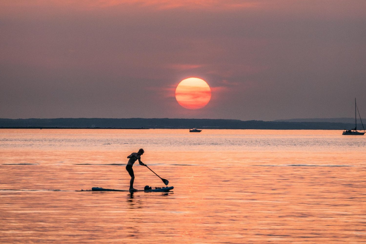 Standuppaddler auf dem Wasser bei Sonnenuntergang