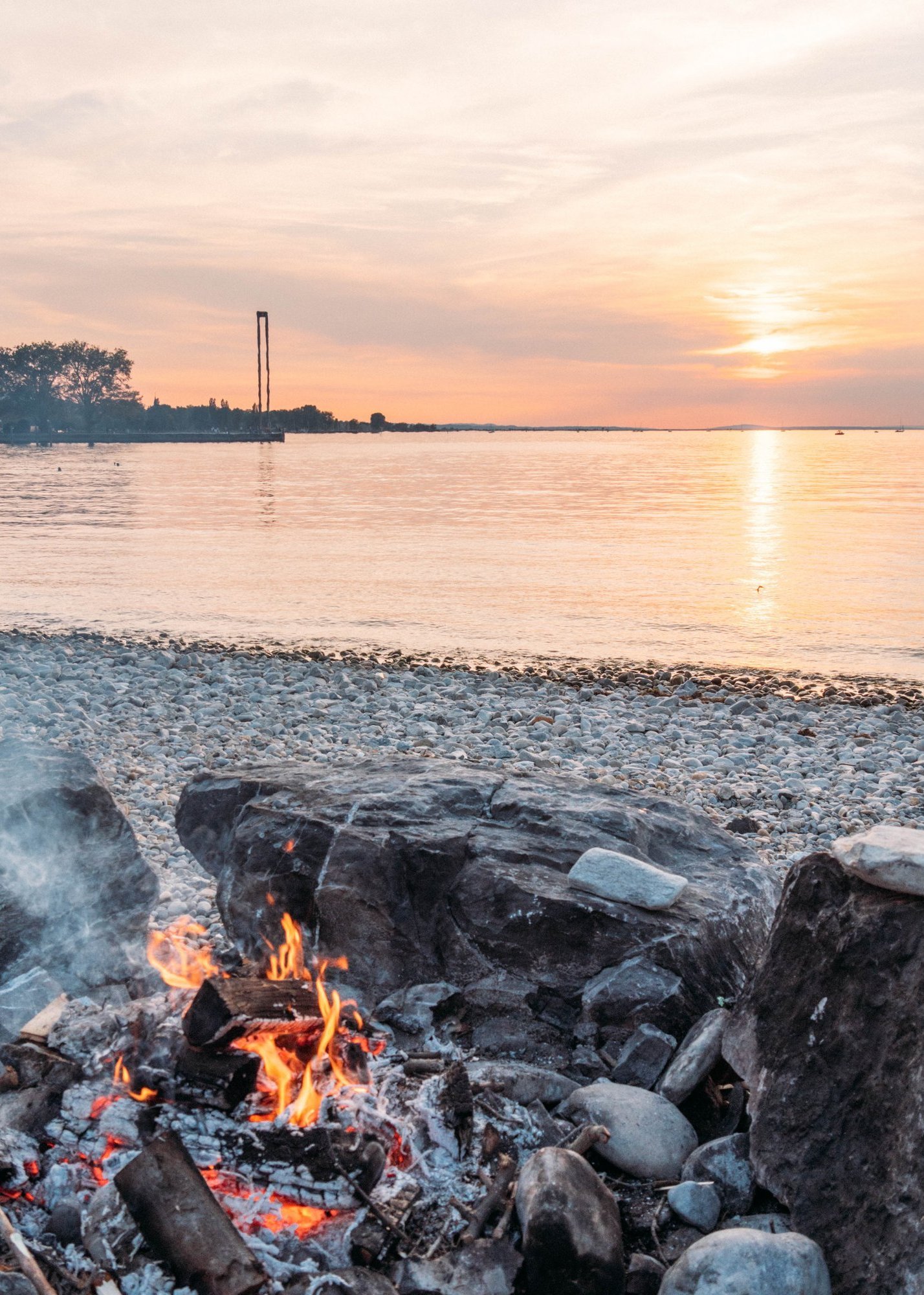 Ein Lagerfeuer im Sonnenuntergang am Ufer des Bodensees
