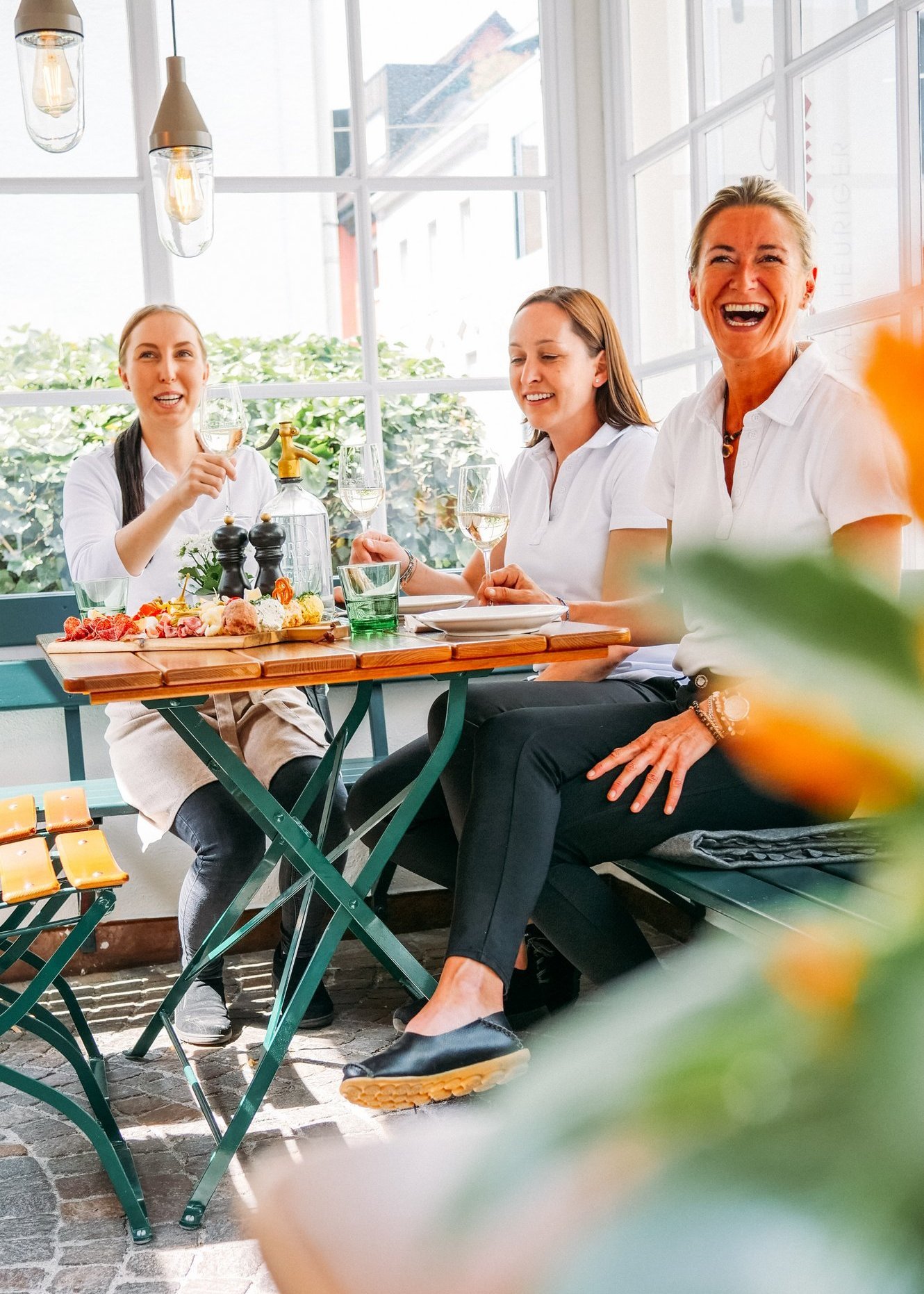 Drei Frauen genießen ein Essen im Maurachbund Bregenz und lächeln in die Kamera