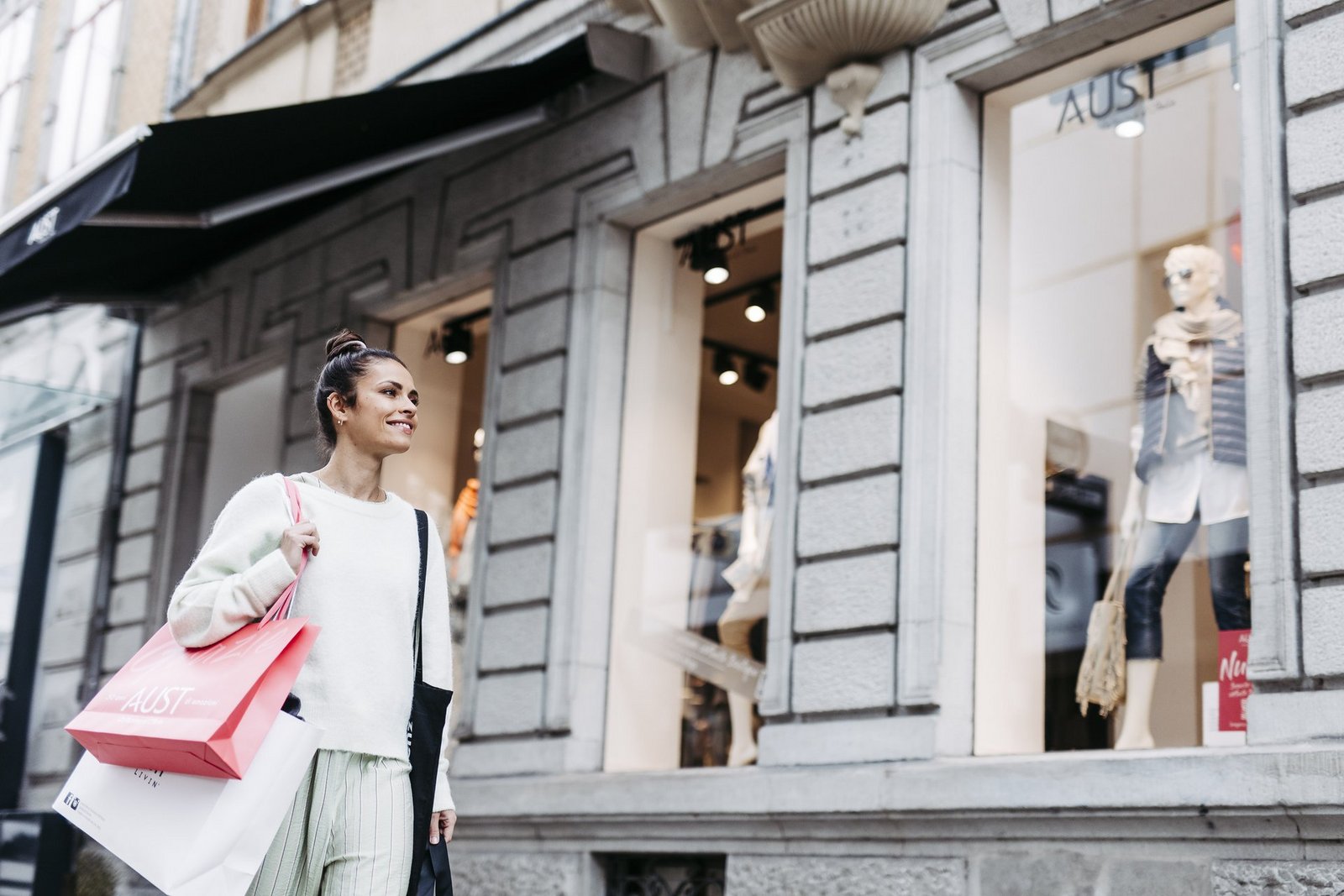 Eine Frau schlendert mit Einkaufstüten durch die Stadt
