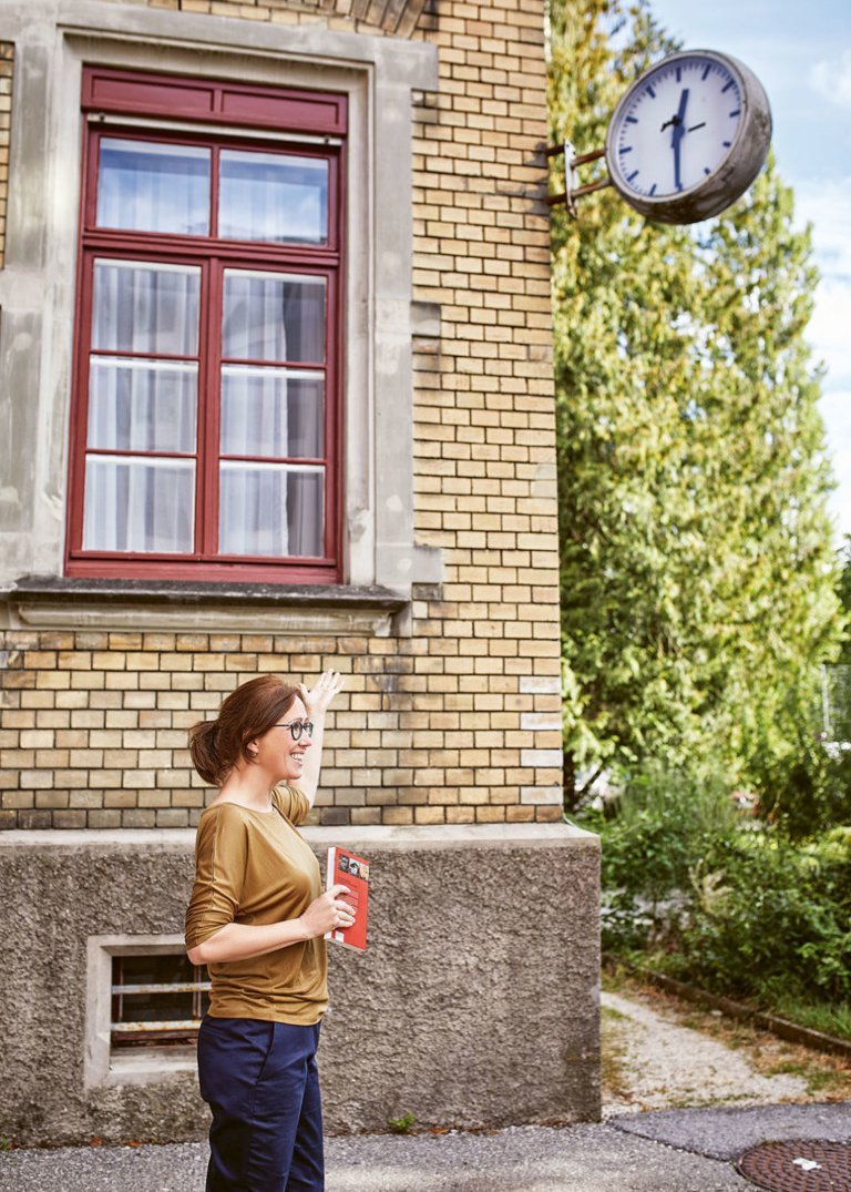 Eine Stadtführerin vor einem alten Backsteinhaus und einer Uhr