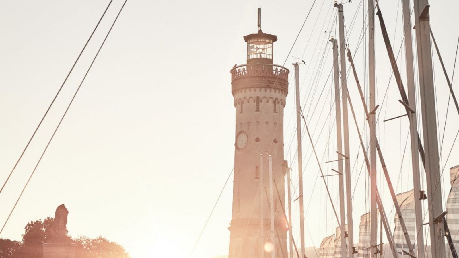 Die untergehende Sonne hinter dem Leuchtturm am Hafen in Lindau