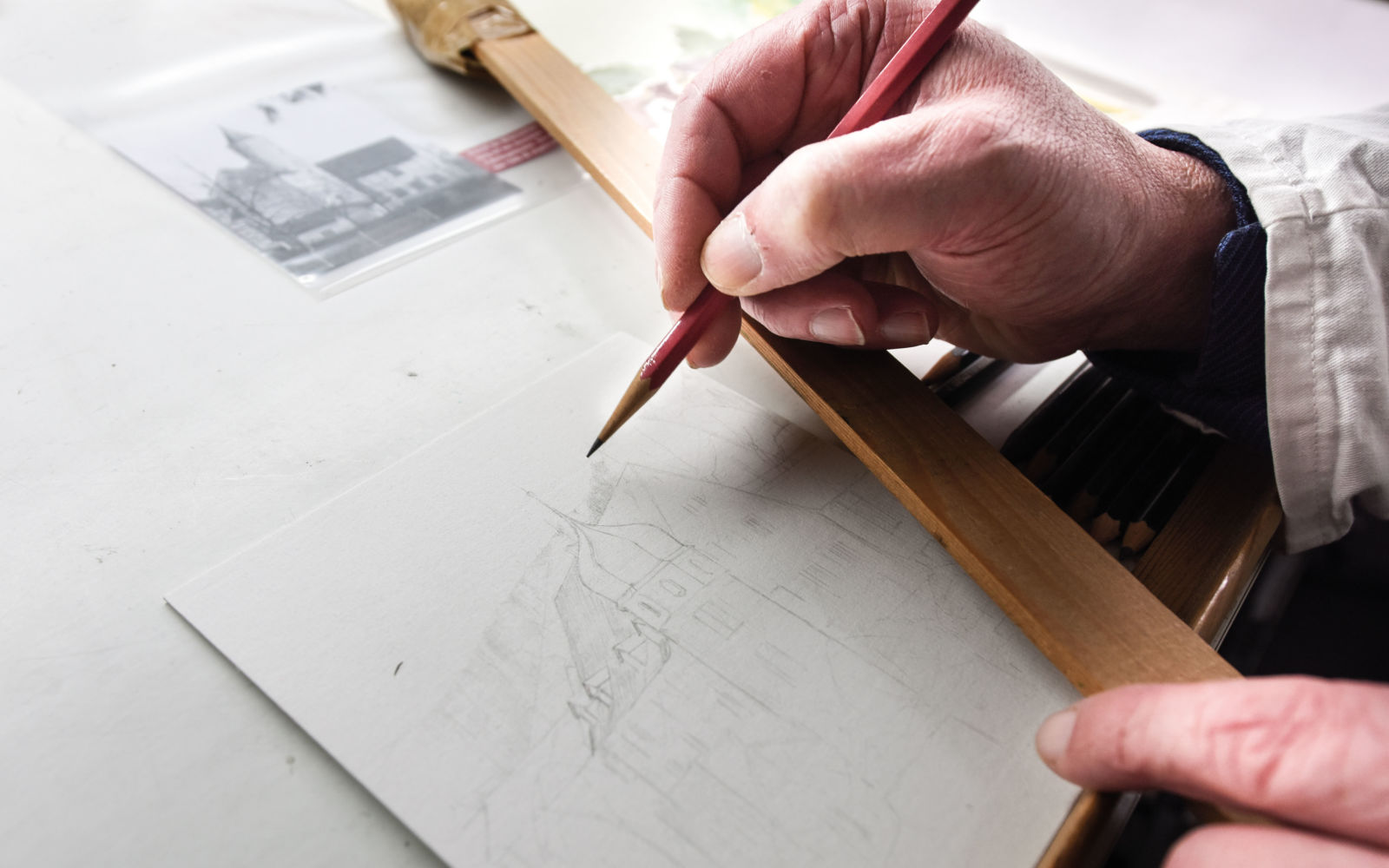 Ein Mann zeichnet mit Bleistift und Lineal eine Karte.