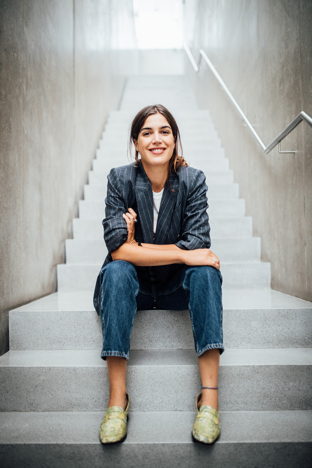 Eine junge Dame sitzt auf den Stufen des Kunsthauses Bregenz und lächelt in die kamera