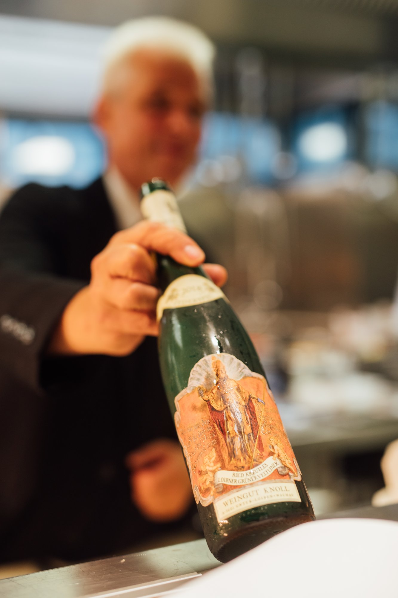 Der Kellner im Casino Bregenz reicht eine hochwertige Weinflasche in Richtung Kamera
