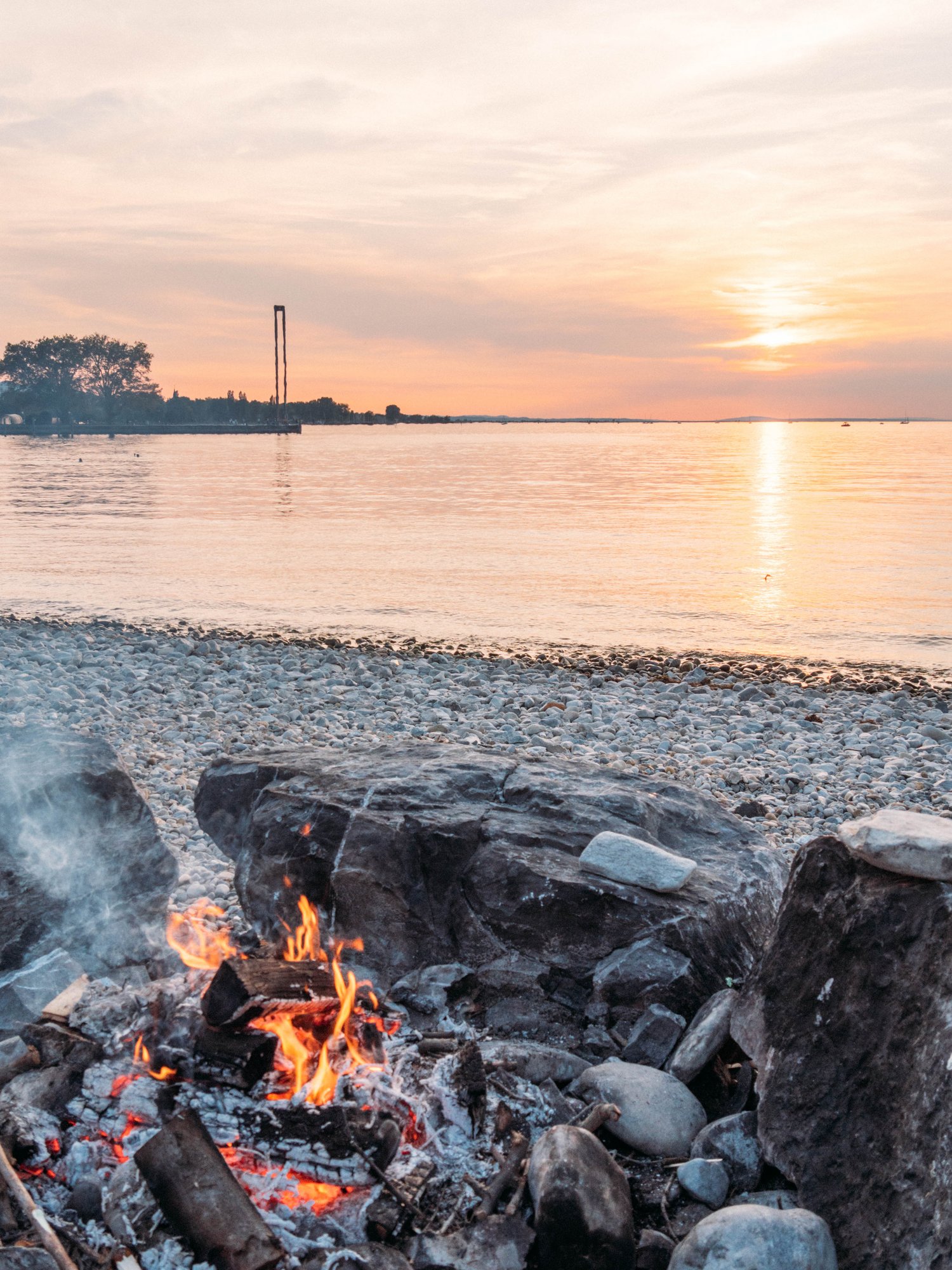 Ein Lagerfeuer im Sonnenuntergang am Ufer des Bodensees