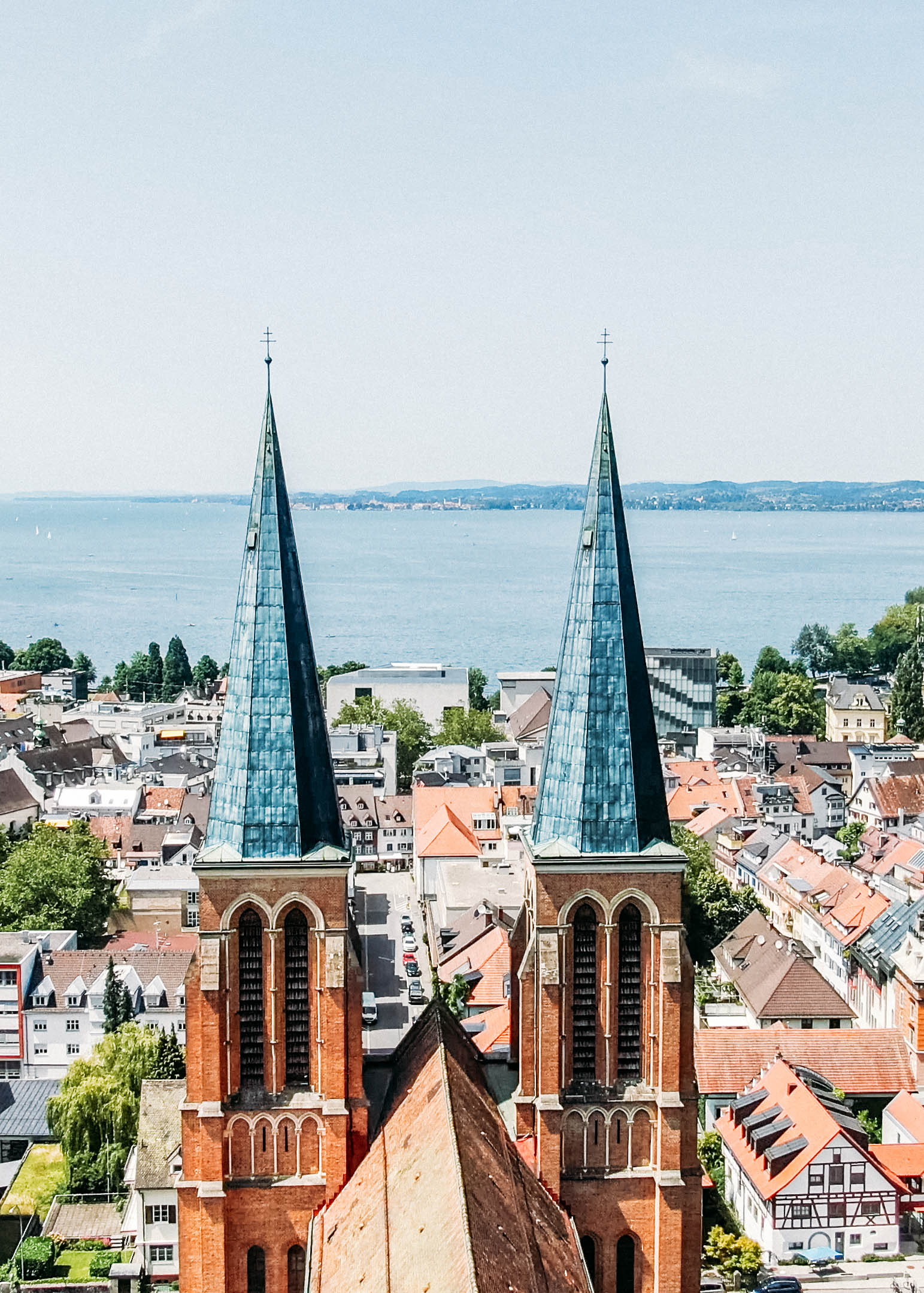 Die zwei Backsteintürme der Herz-Jesu Kirche vor dem sommerlichen Bregenz